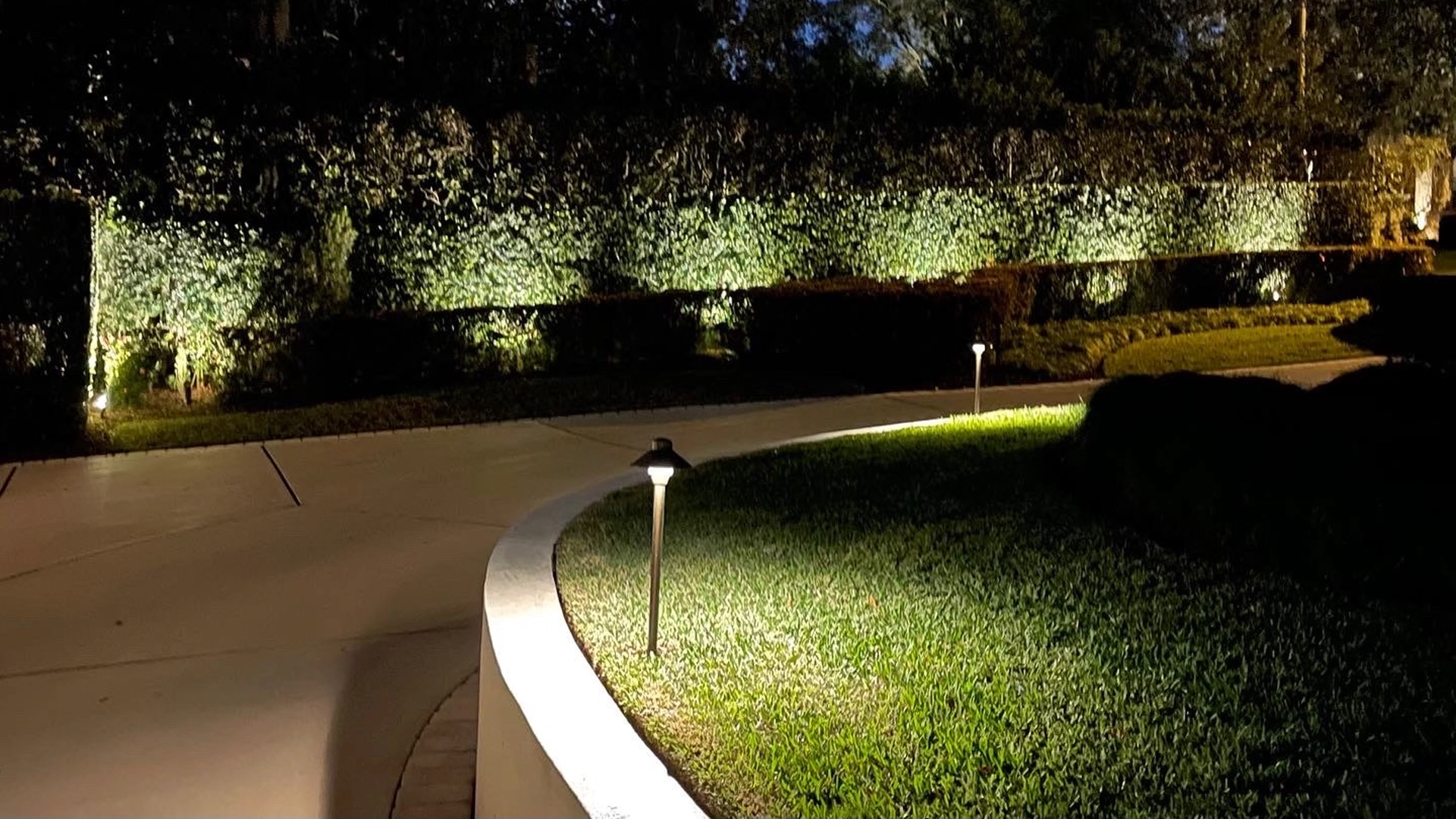 Elegant LED safety walkway lighting in Winter Park, Central Florida, highlighting a curved driveway and trimmed hedges